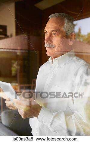 Senior man at home, using digital tablet View Large Photo Image Stock Photo - Senior man at home, using digital tablet. Fotosearch