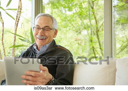 Senior man at home, using digital tablet View Large Photo Image Stock Photography - Senior man at home, using digital tablet. Fotosearch