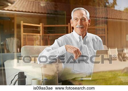 Stock Image - Senior man at home, using laptop. Fotosearch