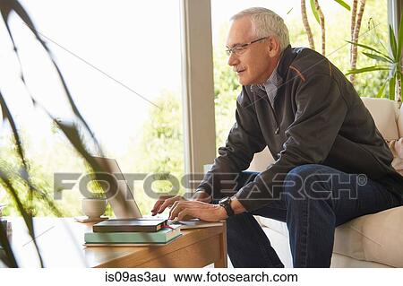 Senior man at home, using laptop View Large Photo Image Stock Photograph - Senior man at home, using laptop. Fotosearch