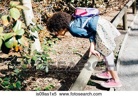 Side view of girl leaning forward over fence to smell flowers View Large Photo Image Stock Photography - Side view of girl leaning forward over fence to smell flowers. Fotosearch