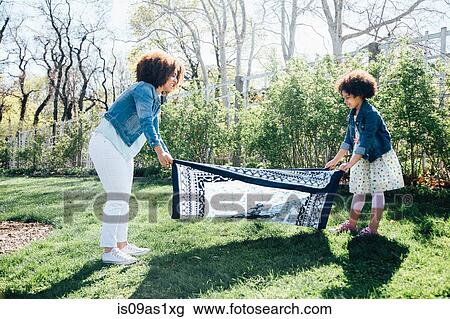 Side view of mother and daughter laying out blanket on grass View Large Photo Image Stock Image - Side view of mother and daughter laying out blanket on grass. Fotosearch