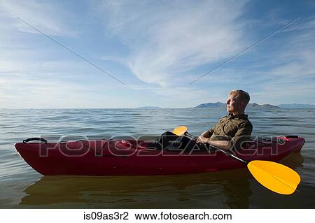 Stock Image - Side view of young man in kayak on water holding paddles, eyes closed, Great Salt Lake, Utah, USA. Fotosearch