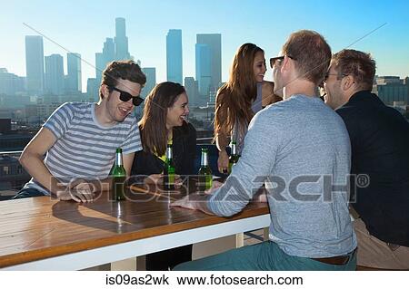 Six adult friends talking and drinking beer at rooftop bar with Los Angeles skyline, USA View Large Photo Image Stock Image - Six adult friends talking and drinking beer at rooftop bar with Los Angeles skyline, USA. Fotosearch