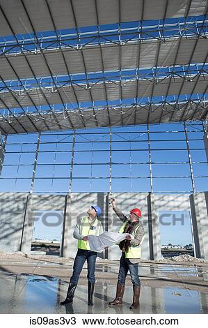 Stock Image - Surveyor and architect looking up at construction frame. Fotosearch