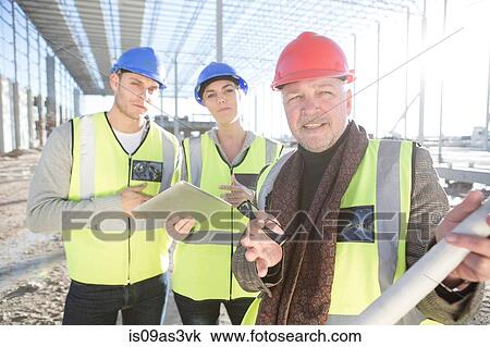 Stock Image - Surveyor explaining to builders on construction site. Fotosearch