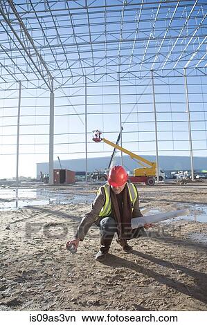Surveyor marking floor area with spray can on construction site View Large Photo Image Picture - Surveyor marking floor area with spray can on construction site. Fotosearch