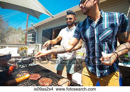 Two mid adult brothers barbecuing in garden View Large Photo Image Picture - Two mid adult brothers barbecuing in garden. Fotosearch