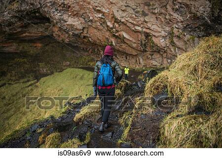 Two tourists walking down path at Seljalandsfoss waterfall, Iceland View Large Photo Image Stock Photo - Two tourists walking down path at Seljalandsfoss waterfall, Iceland. Fotosearch