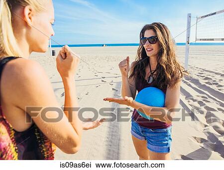 Two young women on beach, standing by volleyball net, holding ball, playing rock, scissors, stone View Large Photo Image Stock Image - Two young women on beach, standing by volleyball net, holding ball, playing rock, scissors, stone. Fotosearch