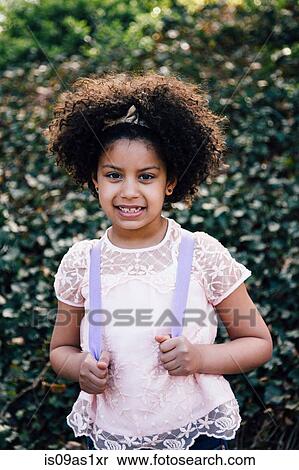 Stock Photography - Waist up portrait of girl wearing backpack, looking at camera smiling. Fotosearch