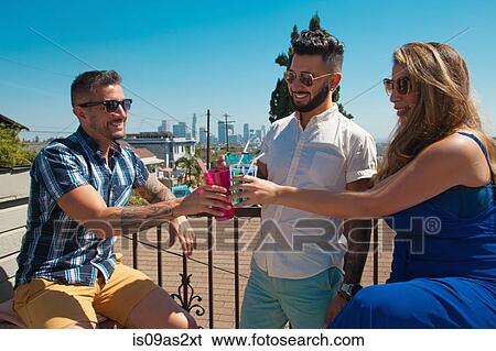 Woman and two mid adult brothers toasting with cocktails on patio View Large Photo Image Stock Photograph - Woman and two mid adult brothers toasting with cocktails on patio. Fotosearch