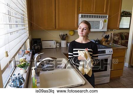 Stock Photography - Woman daydreaming in kitchen. Fotosearch