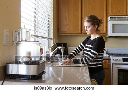 Stock Photography - Woman washing up in kitchen. Fotosearch