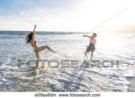 Young couple on beach, fooling around in sea View Large Photo Image Picture - Young couple on beach, fooling around in sea. Fotosearch