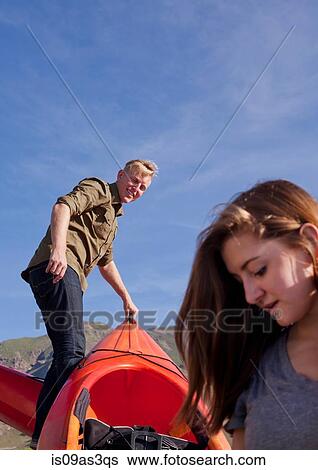 Stock Photograph - Young couple preparing orange kayak. Fotosearch