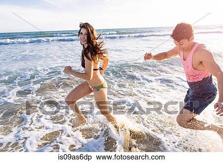 Stock Photography - Young couple running in sea. Fotosearch