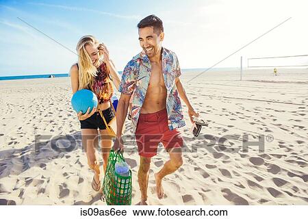 Young couple walking on beach, ready for picnic View Large Photo Image Stock Image - Young couple walking on beach, ready for picnic. Fotosearch