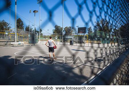 Young male basketball player behind court fence looking at basketball hoop View Large Photo Image Stock Image - Young male basketball player behind court fence looking at basketball hoop. Fotosearch