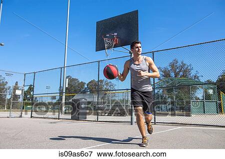 Young male basketball player running with ball on basketball court View Large Photo Image Stock Photo - Young male basketball player running with ball on basketball court. Fotosearch
