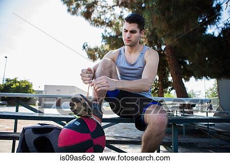 Young male basketball player sitting on bench tying trainer lace View Large Photo Image Stock Image - Young male basketball player sitting on bench tying trainer lace. Fotosearch