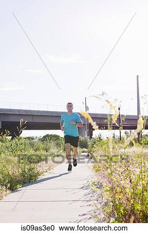 Young male runner running along path View Large Photo Image Stock Image - Young male runner running along path. Fotosearch
