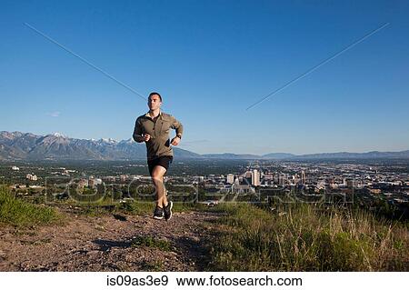 Young male runner running along track above city in valley View Large Photo Image Stock Photo - Young male runner running along track above city in valley. Fotosearch