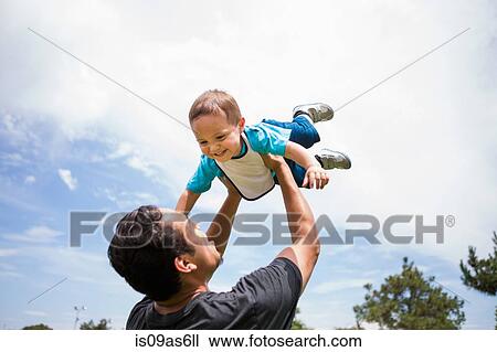 Young man playing lifting up toddler brother in park View Large Photo Image Stock Image - Young man playing lifting up toddler brother in park. Fotosearch