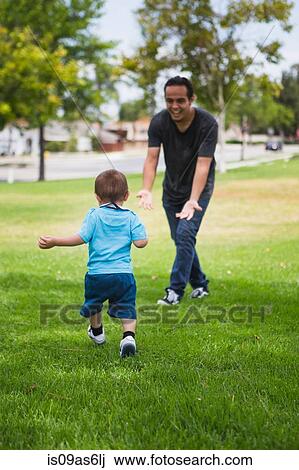 Young man playing with toddler brother in park View Large Photo Image Stock Image - Young man playing with toddler brother in park. Fotosearch