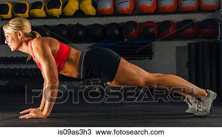 Young woman doing push ups in gym View Large Photo Image Stock Image - Young woman doing push ups in gym. Fotosearch