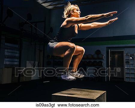 Young woman jumping mid air on gym box with arms reaching out View Large Photo Image Stock Photograph - Young woman jumping mid air on gym box with arms reaching out. Fotosearch