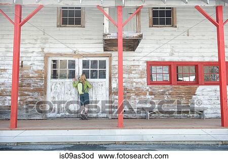 Stock Image - Young woman looking through window, Independence Mine State Historical Park, Hatcher Pass, Matanuska Valley, Palmer, Alaska, USA. Fotosearch