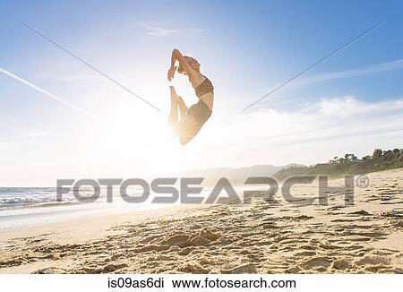 Young woman on beach, leaping in air, sunset View Large Photo Image Stock Image - Young woman on beach, leaping in air, sunset. Fotosearch