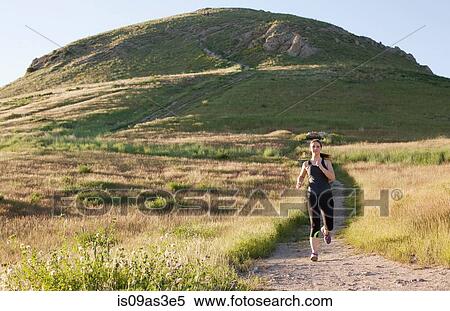 Stock Photography - Young woman running on hillside track. Fotosearch