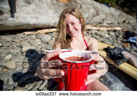 Young woman sitting on rocky beach, holding drinks, smiling, Short Sands Beach, Oregon, USA View Large Photo Image Stock Photo - Young woman sitting on rocky beach, holding drinks, smiling, Short Sands Beach, Oregon, USA. Fotosearch