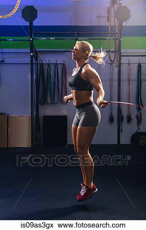 Stock Photo - Young woman skipping with skipping rope in gym. Fotosearch
