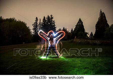 Young woman, standing in field at dusk, arms and legs outstretched in star shape, light trail tracing body shape View Large Photo Image Stock Image - Young woman, standing in field at dusk, arms and legs outstretched in star shape, light trail tracing body shape. Fotosearch