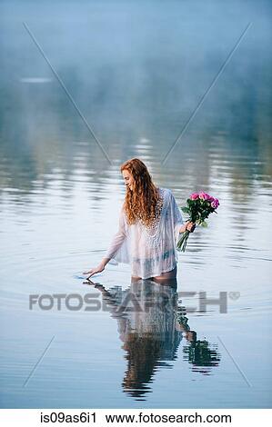Young woman standing in lake holding bunch of roses and rippling surface with her fingers View Large Photo Image Stock Image - Young woman standing in lake holding bunch of roses and rippling surface with her fingers. Fotosearch