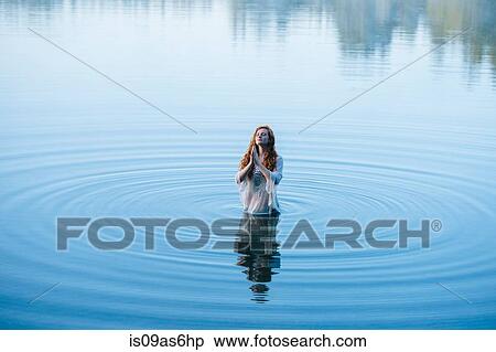 Young woman standing in lake ripples praying with eyes closed View Large Photo Image Stock Photography - Young woman standing in lake ripples praying with eyes closed. Fotosearch