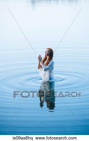 Young woman standing in lake ripples with eyes closed and hands together View Large Photo Image Stock Photography - Young woman standing in lake ripples with eyes closed and hands together. Fotosearch