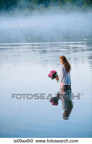 Young woman standing in misty lake holding bunch of pink roses View Large Photo Image Stock Image - Young woman standing in misty lake holding bunch of pink roses. Fotosearch