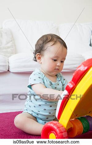Baby boy sitting on floor playing with toy View Large Photo Image Stock Image - Baby boy sitting on floor playing with toy. Fotosearch