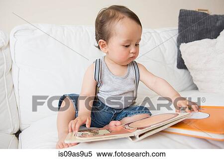 Baby boy sitting on sofa looking at picture book View Large Photo Image Stock Photography - Baby boy sitting on sofa looking at picture book. Fotosearch