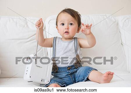 Baby boy sitting on sofa playing with transistor radio aerial View Large Photo Image Stock Image - Baby boy sitting on sofa playing with transistor radio aerial. Fotosearch