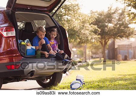 Boy and younger sister preparing for football practice whist sitting in car boot View Large Photo Image Stock Image - Boy and younger sister preparing for football practice whist sitting in car boot. Fotosearch