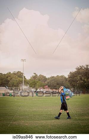 Boy football player carrying bag of footballs on practice pitch View Large Photo Image Stock Photograph - Boy football player carrying bag of footballs on practice pitch. Fotosearch