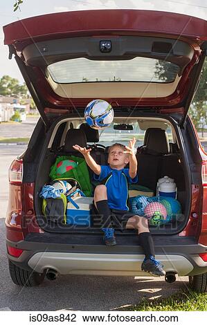 Boy football player sitting in car boot throwing and catching football View Large Photo Image Stock Image - Boy football player sitting in car boot throwing and catching football. Fotosearch
