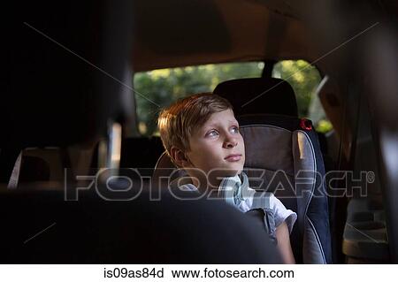 Stock Image - Boy in car back seat gazing out through window. Fotosearch