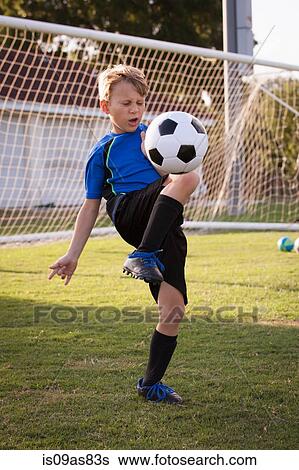 Boy playing keepy uppy with football on pitch View Large Photo Image Stock Photograph - Boy playing keepy uppy with football on pitch. Fotosearch