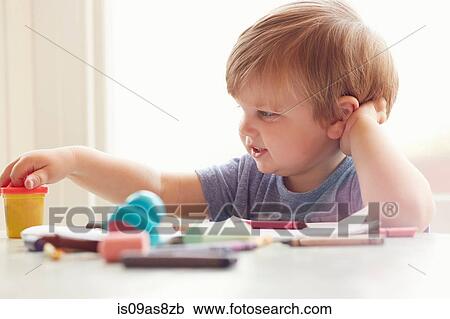Boy sitting at table leaning on elbow looking at art supplies View Large Photo Image Stock Image - Boy sitting at table leaning on elbow looking at art supplies. Fotosearch